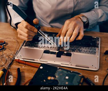 Die Teile wieder zusammenfügen. Ausgeschnittene Aufnahme einer unkenntlichen Computertechnikerin, die in ihrer Werkstatt einen Laptop repariert hat. Stockfoto