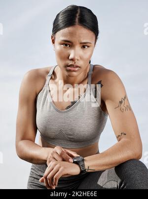 Diese Uhr sagt nicht nur die Zeit. Aufnahme einer sportlichen jungen Frau, die ihre Smartwatch beim Training im Freien überprüft. Stockfoto