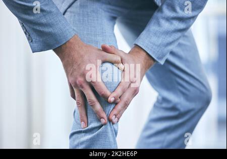 Ich sollte mir mehr Zeit nehmen, um mich um meine Gesundheit zu kümmern. Kurzer Schuss eines Geschäftsmannes, der sein Knie vor Schmerzen hält. Stockfoto