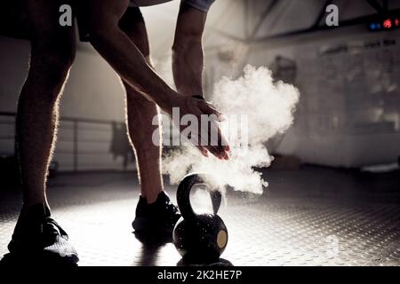 Gehen Sie nicht durchs Leben und sind besessen davon, was hätte sein können. Aufnahme eines unbekannten Mannes, der sich beim Training mit einer Kugelhantel in einem Fitnessstudio Kreide an den Händen reibt. Stockfoto