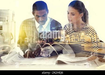Sicherstellen, dass ihr Design perfekt ist. Mehrfachaufnahme von zwei jungen Kollegen, die im Büro arbeiten, übereinander einer Stadt. Stockfoto