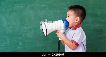 Kind Junge Kindergarten Vorschule in Studentenuniform durch Megaphon sprechen Gegen Stockfoto