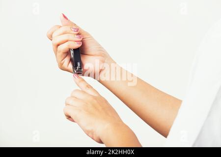 Frau schneidet Nägel am Finger mit einem Nagelschneider Stockfoto