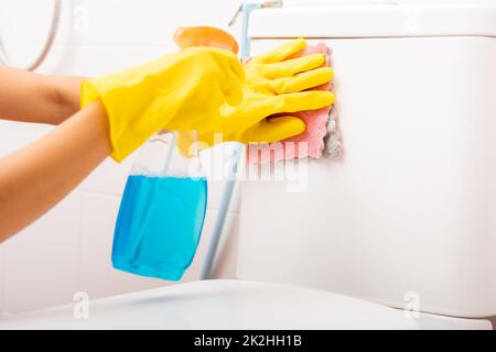 Hand einer asiatischen Frau, die den Toilettensitz mit Flüssigspray und einem rosa Tuch abwischte, um die Toilette im Haus zu reinigen Stockfoto