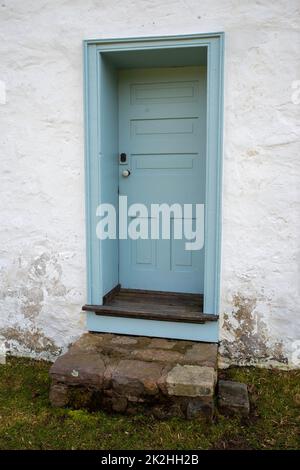 Blaue Holztür im Kolonialstil in einem weiß getünchten Steinhaus Stockfoto