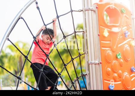 Asiatisches Kind lächelt beim Klettern draußen auf dem Spielplatz Stockfoto