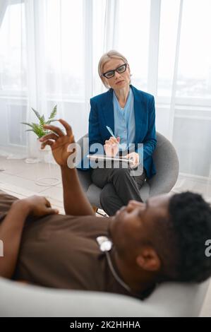 Psychologe macht Notizen, während ein männlicher Soldat spricht Stockfoto