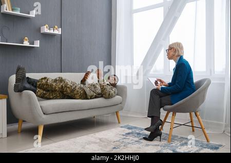 Psychologe macht Notizen, während ein männlicher Soldat spricht Stockfoto