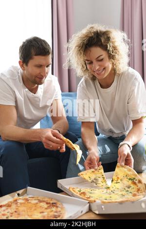 Glückliches Paar, das zu Hause leckere Pizza isst Stockfoto