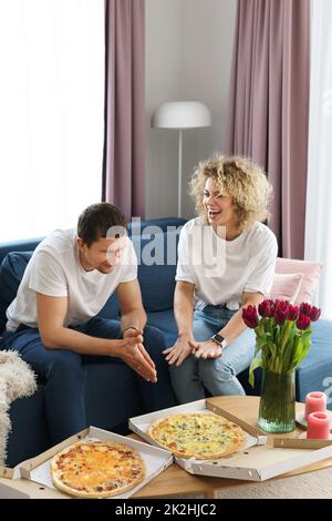 Glückliches Paar, das zu Hause leckere Pizza isst Stockfoto