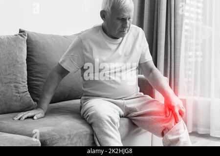 Seniorenmensch mit Knieschmerzen zu Hause. Stockfoto