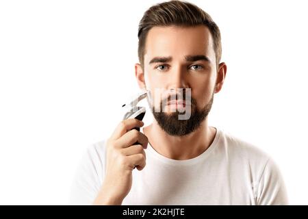 Ein hübscher bärtiger Mann verwendet einen elektrischen Trimmer Stockfoto