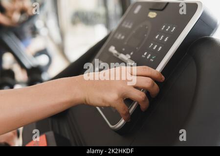 Frau, die die Einstellungen auf einem Laufband in einem Fitnessstudio ändert Stockfoto