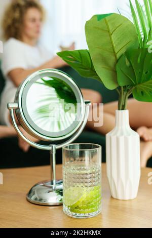 Runder Spiegel und ein Glas Entgiftungswasser auf dem Tisch Stockfoto