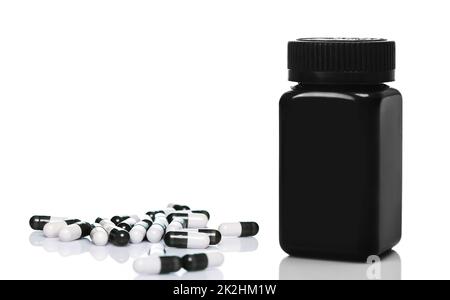 Schwarzes Kunststoffglas und Kapseln auf weißem Hintergrund Stockfoto