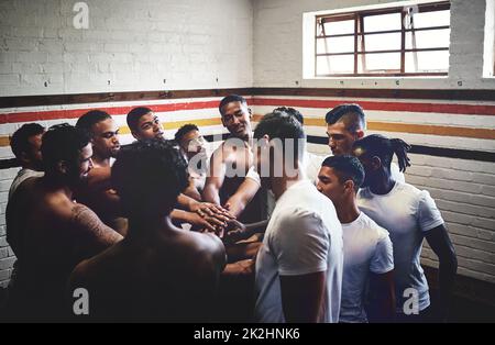 Sammeln im Geiste des Gewinnens. Eine kurze Aufnahme einer Gruppe hübscher junger Rugby-Spieler, die in einer Umkleidekabine zusammenstehen. Stockfoto