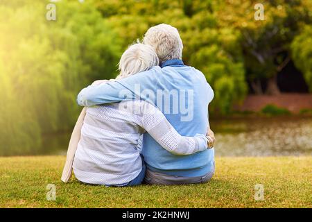 Sich gegenseitig festhalten. Aufnahme eines älteren Paares, das den Tag gemeinsam in einem Park genießt. Stockfoto