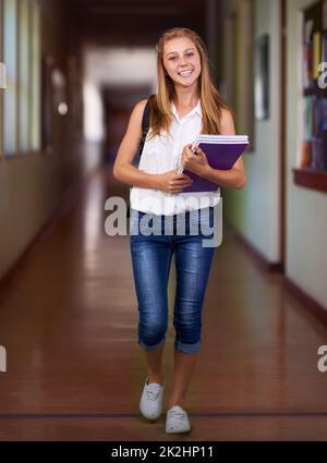 Sie ist eine fleißige Schülerin. Aufnahme eines jungen Mädchens in ihrem Schulflur. Stockfoto