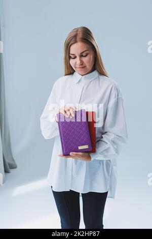 Eine stilvolle Frau hält ein Notizbuch in den Händen. Notizbuch für Geschäftsunterlagen. Stockfoto