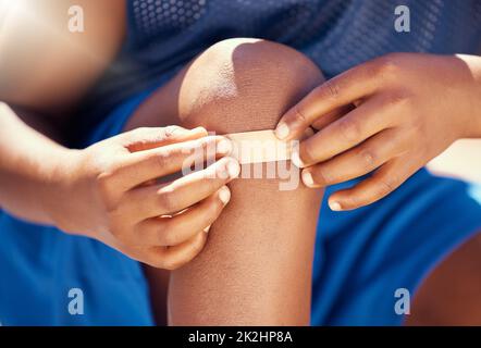 Kinder, Unfall und Gips mit einem Band helfen dem Jungen mit einer Verletzung, Wunde oder Schmerzen am Knie. Kinder, schneiden und heilen mit den Händen eines männlichen Kindes Stockfoto