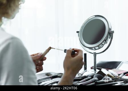 Runder Spiegel für Make-up und weibliche Hände mit flüssigem Versteck Stockfoto