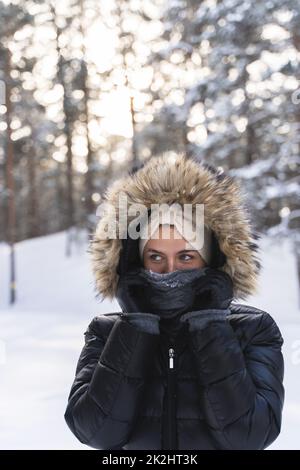 Junge Frau trägt eine Daunenjacke mit Hoodie an kalten Wintertagen Stockfoto