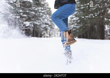 Frau trägt Schaffellstiefel und tritt Schnee Stockfoto