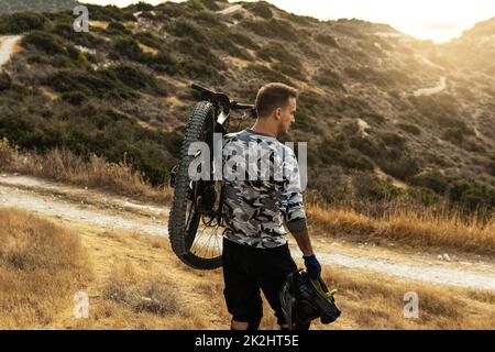 Professioneller Downhillfahrer, der sein Fahrrad auf der Schulter trägt Stockfoto