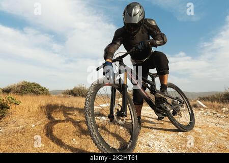 Downhillfahrer voll ausgestattet mit Schutzausrüstung und seinem Fahrrad Stockfoto