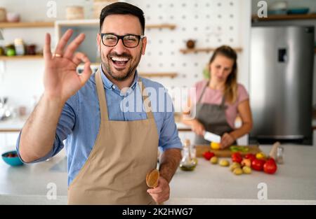 Porträt eines gutaussehenden glücklichen Mannes, der zu Hause kocht und in der Küche Essen zubereitet. Stockfoto