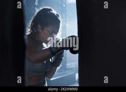 Schmerz in Kraft verwandeln. Aufnahme einer sportlichen jungen Frau, die im Fitnessstudio boxte. Stockfoto