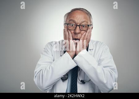 Wie werden wir diesen Fall lösen? Aufnahme eines älteren männlichen Arztes in einem Studio vor grauem Hintergrund. Stockfoto