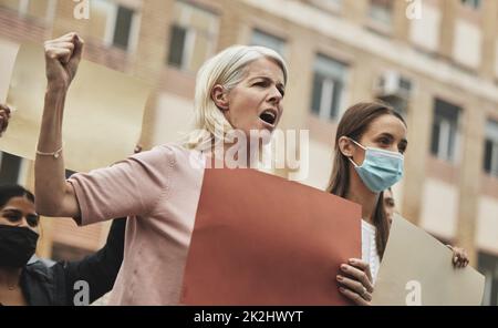 Kämpfen für das, woran sie glauben. Aufnahme einer Gruppe von Menschen, die während der Teilnahme an einer politischen Kundgebung Schilder halten. Stockfoto