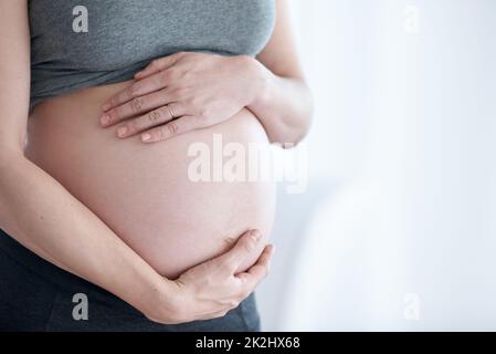 Bereit für die Mutterschaft. Kurzer Schuss einer Schwangeren, die in ihrem Haus steht. Stockfoto