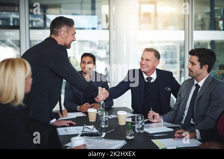 Ich bin froh, dass alle dem zustimmen. Aufnahme von zwei fröhlichen Geschäftsleuten, die sich in einem Sitzungssaal im Büro einig die Hände schüttelten. Stockfoto