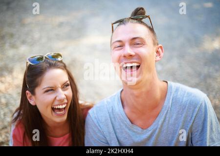 Jung im Herzen. Zwei junge Menschen lächeln fröhlich, während sie draußen sitzen. Stockfoto