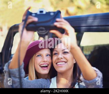 Perfekte Momente im Bild. Aufnahme einer zwei Freundinnen, die auf einer Roadtrip-Reise Selbstporträts machen. Stockfoto