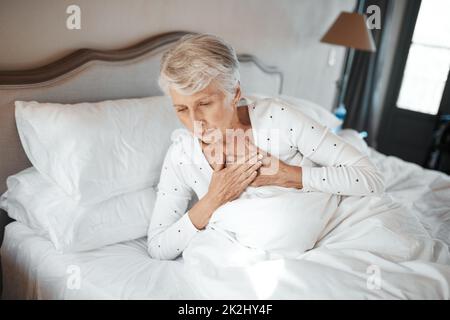 Niemand ist immun. Aufnahme einer älteren Frau mit Brustschmerzen im Bett in einem Pflegeheim. Stockfoto