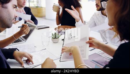 Die Papierkram überblicken. Eine kurze Aufnahme einer Gruppe von Geschäftsleuten, die während eines Meetings am Tisch des Sitzungssaals sitzen. Stockfoto