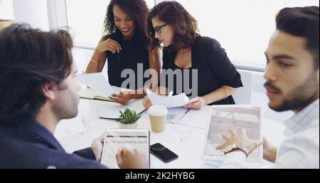 Im Sitzungssaal versammelt. Eine kurze Aufnahme einer Gruppe von Geschäftsleuten, die während eines Meetings am Tisch des Sitzungssaals sitzen. Stockfoto