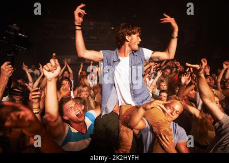 Genießen Sie jeden Song, den die Band spielt. Aufnahme einer großen Menschenmenge bei einem Musikkonzert. Stockfoto