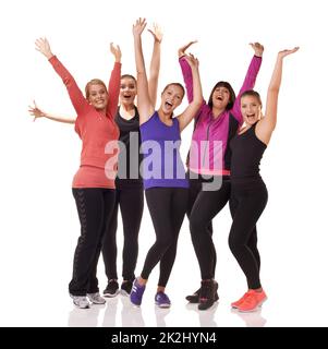 Wir werden zusammenpassen. Eine Gruppe aufgeregter Frauen unterschiedlicher Körperformen, die isoliert auf Weiß stehen, während sie Sportkleidung tragen. Stockfoto