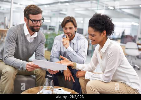 Ich kann die Performance des letzten Quartals nicht glauben. Aufnahme einer Gruppe junger Fachleute, die über Papierkram diskutieren. Stockfoto