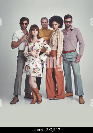 Nichts wie im Stil von 70s. Eine Studioaufnahme einer Gruppe von Menschen, die zusammen stehen, während sie in Retro-70s-Kleidung gekleidet sind. Stockfoto