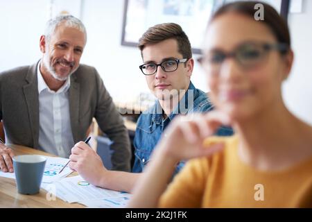 Er ist 100-fokussiert. Porträt eines jungen Geschäftsmannes, der in einer Besprechung zwischen seinen Kollegen sitzt. Stockfoto