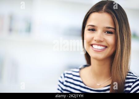 Sie hat das perfekte Lächeln. Porträt einer attraktiven jungen Frau, die zu Hause lächelt und sich entspannt. Stockfoto