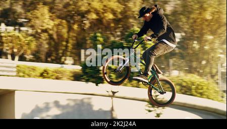 Ein wenig Luft. Ganzkörperaufnahme eines jungen BMX-Reiters, der Tricks in der Stadt macht. Stockfoto