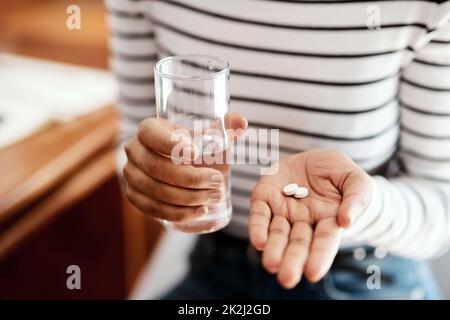 Denn wenn du dich nicht ganz richtig fühlst. Kurzer Schuss einer Frau, die ihre Medikamente zu Hause nimmt. Stockfoto