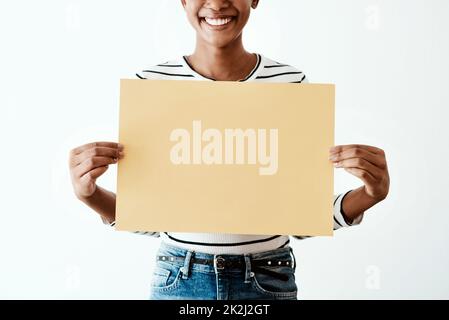 Gelb ist die offizielle fröhliche Farbe. Beschnittene Studioaufnahme einer Frau, die ein gelbes Poster vor weißem Hintergrund hält. Stockfoto