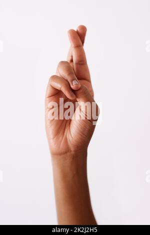 Ich drücke mir die Daumen. Studioaufnahme einer nicht erkennbaren Frau, die die Daumen vor einem weißen Hintergrund drückt. Stockfoto